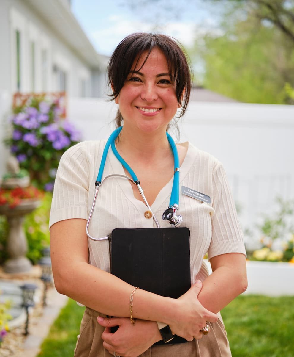 Infirmière souriante en tenue beige, stéthoscope autour du cou, tenant une tablette dans un jardin